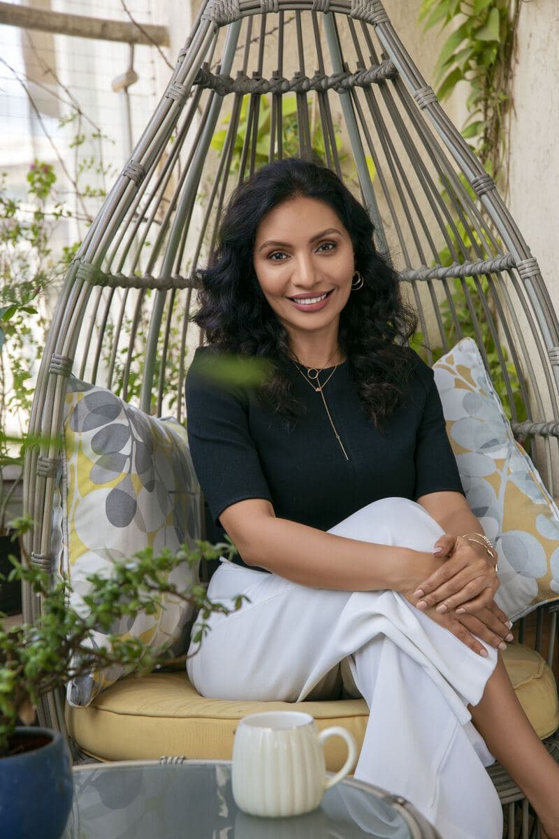 Editorial portrait of Minal Srinivasan seated in a garden chair, from a press feature