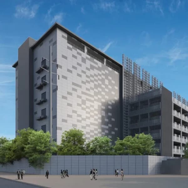 The completed Lumina data centre: a grey panelled block with a louvred plant deck above and street trees along its boundary wall