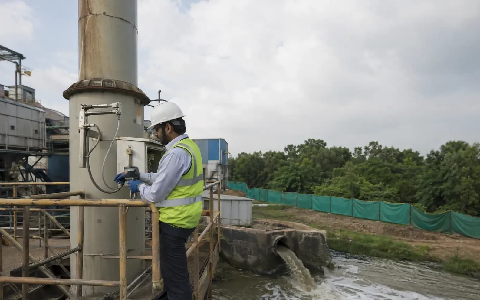 environmental engineer in a hard hat inspecting a stack-emission monitoring poin