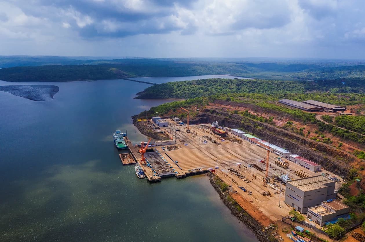 Aerial of the Chowgule Lavgan ship-repair yard at Jaigad: the quay and hardstanding along a forested creek, with vessels alongside and tower cranes over the yard