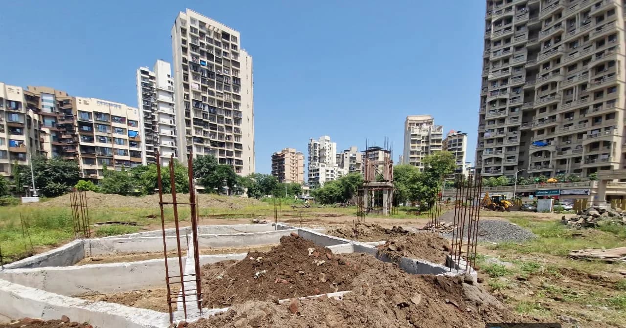 Concrete foundation strips and starter bars set out across the Kharghar park site
