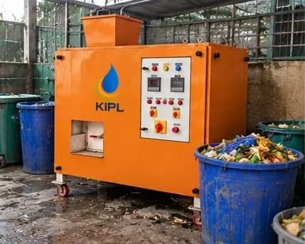 An orange KIPL-branded organic waste converter beside blue bins of segregated food waste