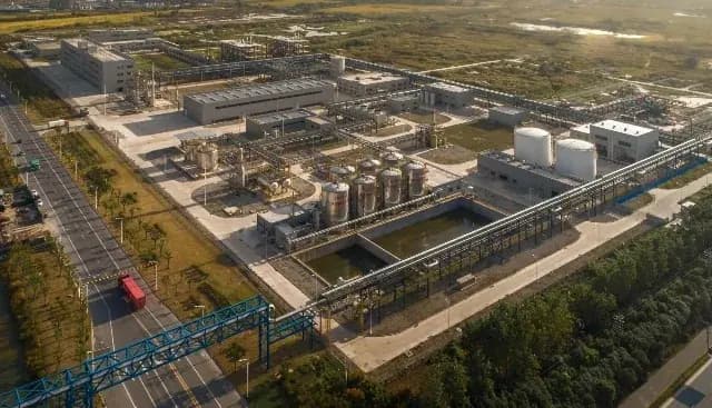 An aerial view of a process plant with tanks, pipe racks and a service road