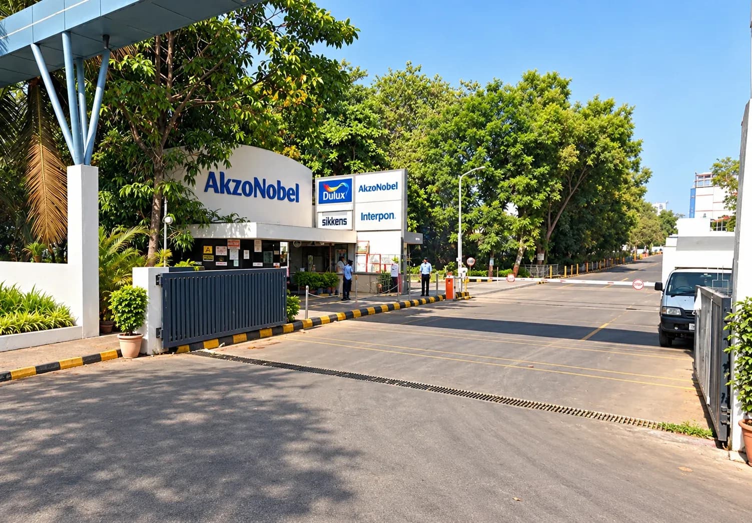 The signed main gate of the AkzoNobel Koparkhairne works, with the security post and tree-lined internal road beyond