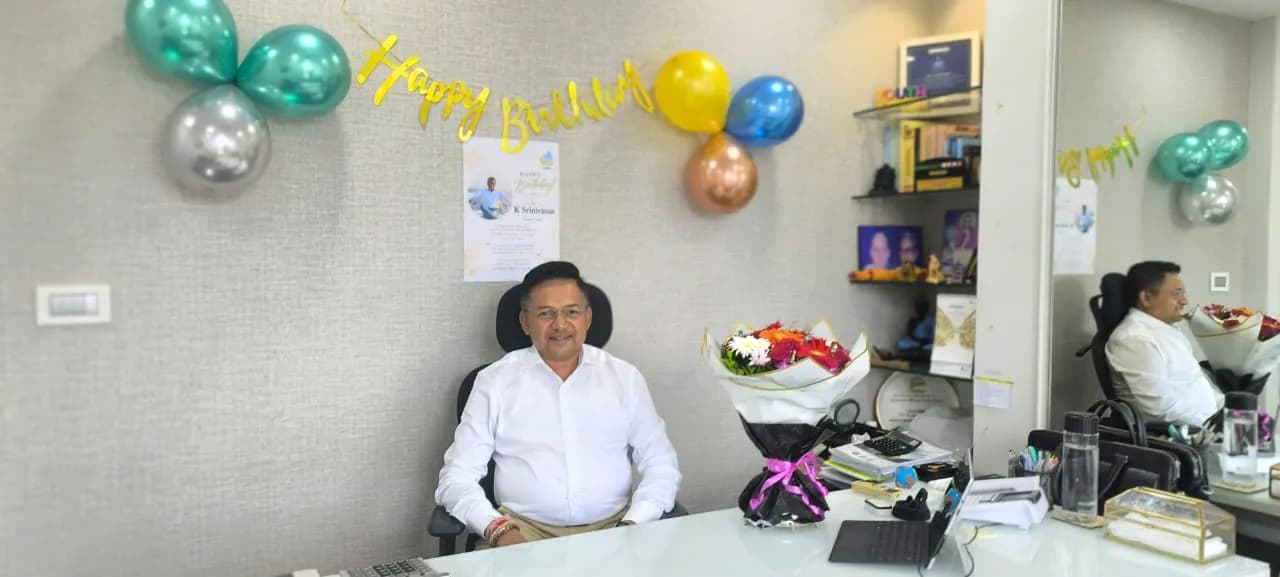 A KIPL colleague at their desk with birthday balloons, a banner and flowers