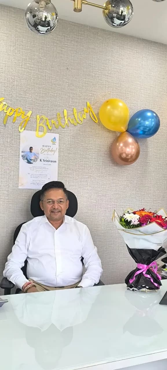 A KIPL colleague at their desk with birthday balloons, a banner and flowers
