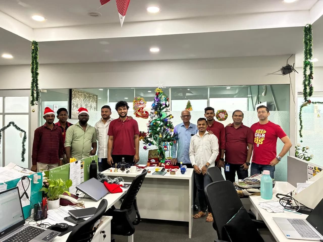 A decorated Christmas tree and KIPL colleagues in Santa hats at the office