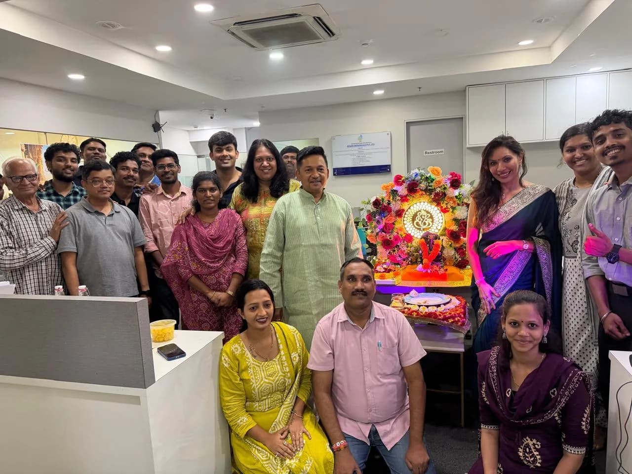 KIPL colleagues gathered around the decorated Ganpati idol at the office