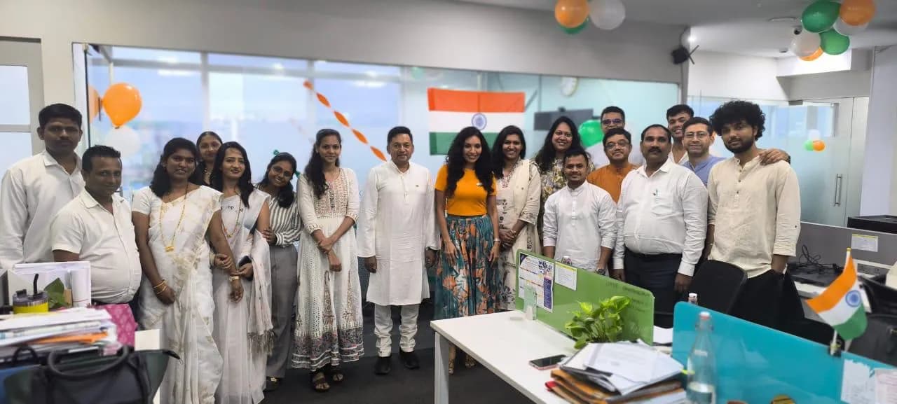 KIPL colleagues dressed in white beside the national flag on Independence Day