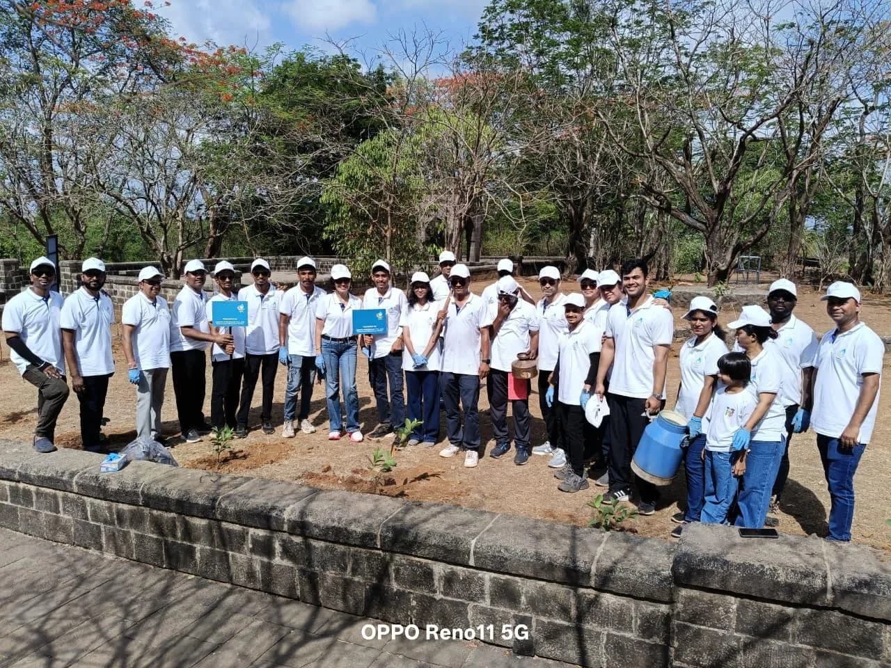 KIPL colleagues planting saplings beside a stone wall on the Raigad outing